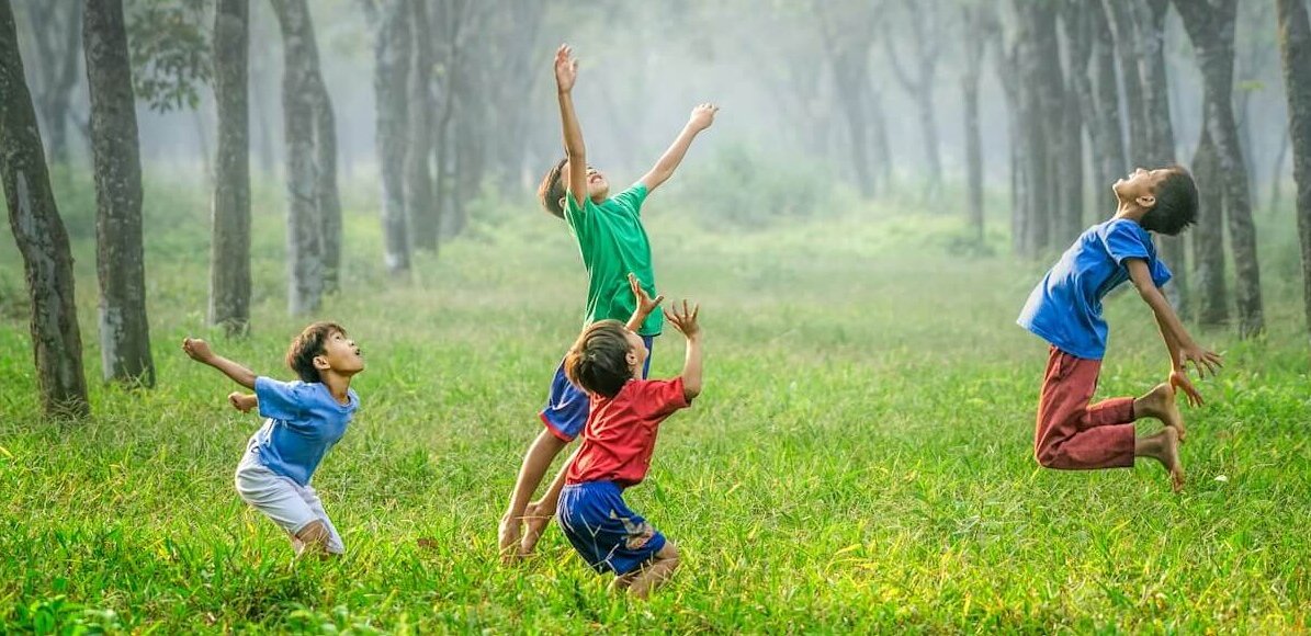 four boy playing ball on green grass